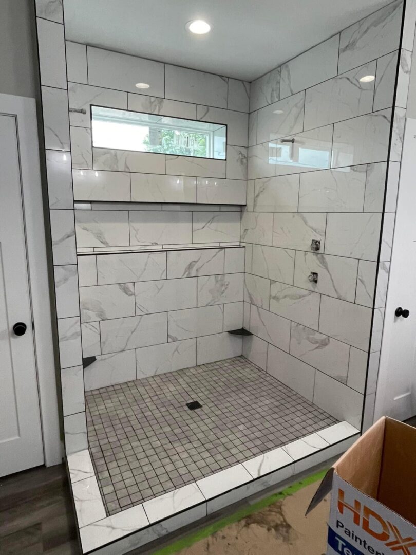 A large tiled shower with a window in the middle.